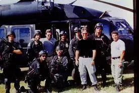 A group of people standing in front of an army helicopter.