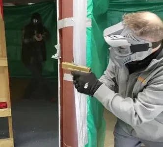 A man holding a gun in front of a wall.