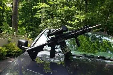 A rifle mounted to the windshield of a car.